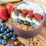 acai bowl topped with granola, blueberries, banana, chia seeds, strawberries and coconut flakes